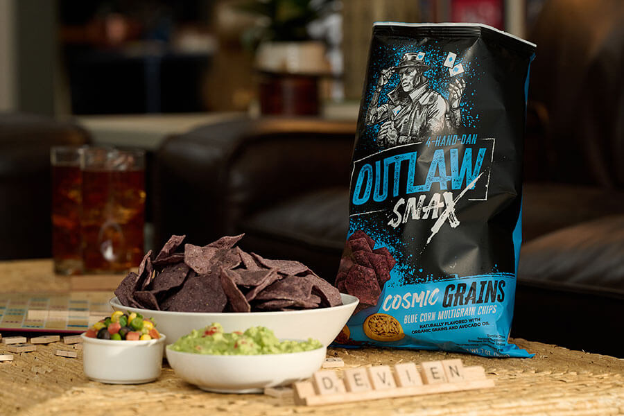Outlaw Snax Cosmic Grains blue corn multigrain tortilla chips served with guacamole dip for snacking.