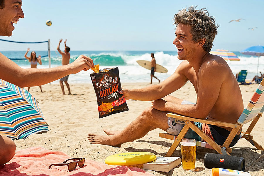 Outlaw Snax Crazy Queso flavored tortilla chips enjoyed during a sunny day at the beach.